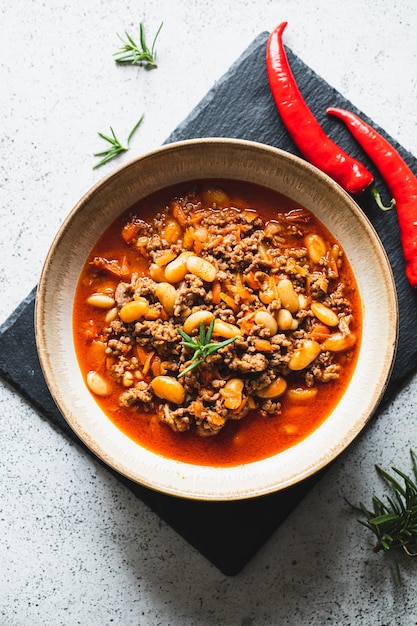 Chili Con Carne in kom op lichtgrijze steen of betonnen ondergrond Mexicaanse keuken Chili con carne gehakt vlees en groenten stoofpot in tomatensaus Bovenaanzicht