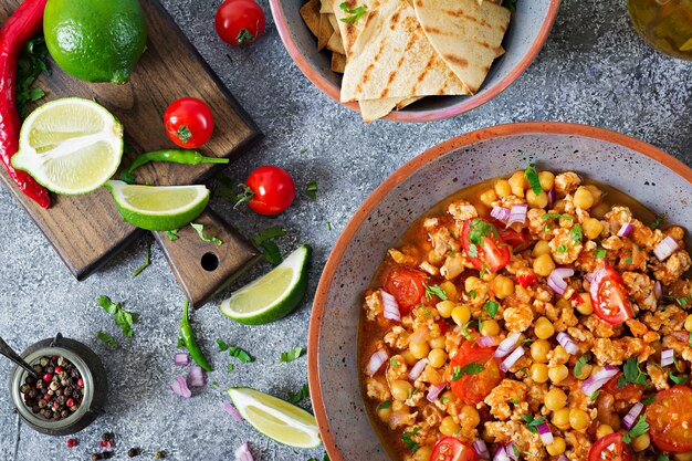 Chili con carne of turkey  with chickpeas served with nachos.  Chili with meat, nachos, lime, hot pepper. Mexican / Texas traditional food. Top view