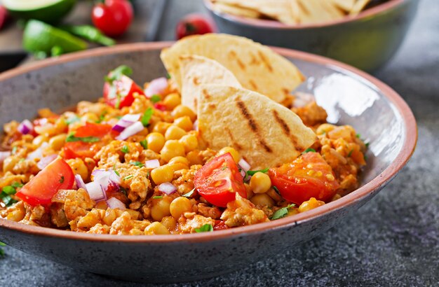 Chili con carne of turkey  with chickpeas served with nachos.  Chili with meat, nachos, lime, hot pepper. Mexican / Texas traditional food.