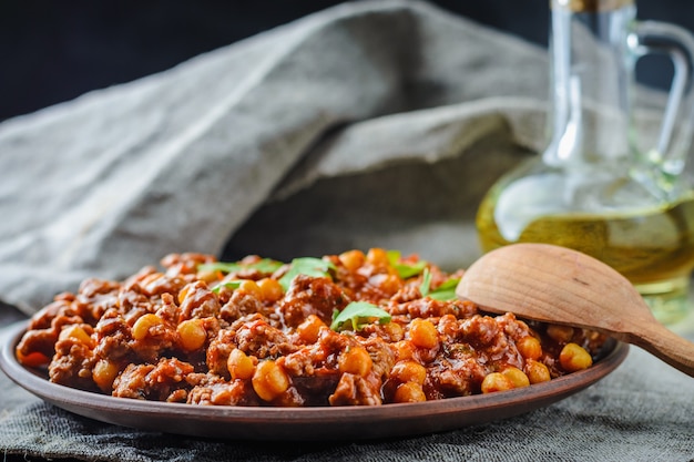 Chili met varkensvlees en kikkererwten op een plaat op donkere achtergrond