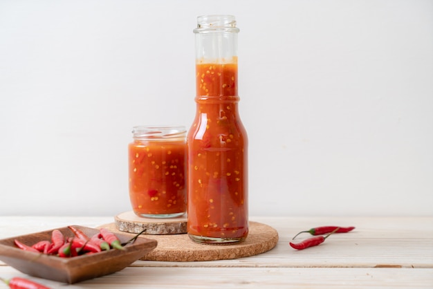 Chili of chilisaus in fles en pot op hout