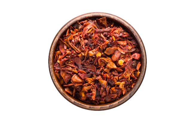 Chili pepper flakes spice in wooden bowl, isolated. Seasoning top view