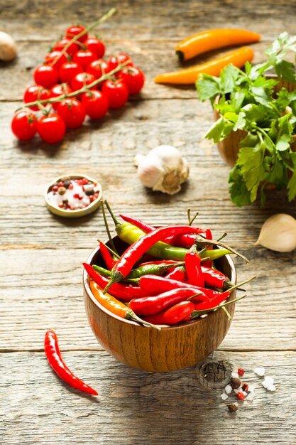Chili pepper is spicy in a wooden bowl. Tomato parsley garlic on wooden rustic background