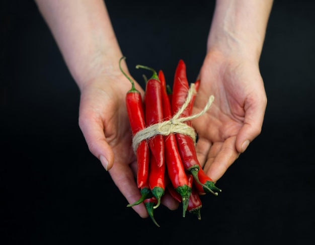 Chili pepper isolated on a black background Knitted hot chili pepper tied with a rope Chili hot pepper clipping path a stack of hot peppers in the hands of a cook