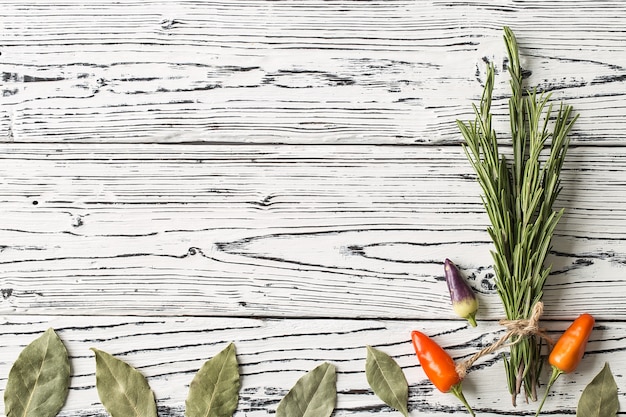  chili pepper and rosemary sprigs with laurel leaves on wooden 