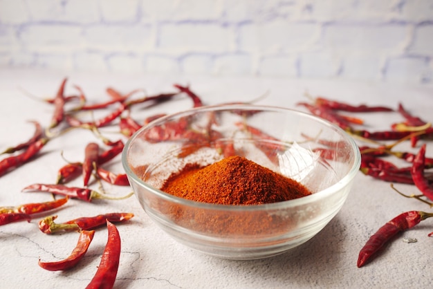 Chili powder and red peppers on table background