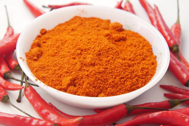 Chili powder and red peppers on table background