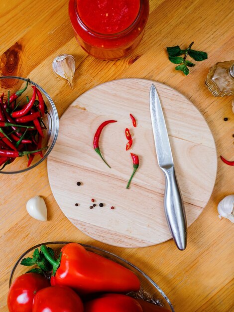 Foto preparazione della salsa di peperoncino piccoli peperoncini piccanti su un tagliere rotondo su un tavolo di legno