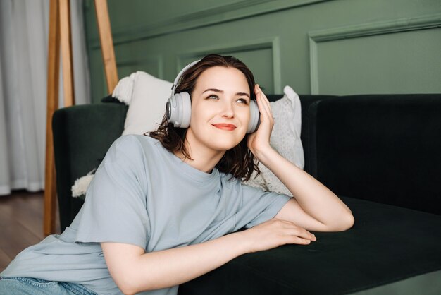 Foto chill time vriendelijke vrouw luistert naar muziek op de bank met draadloze koptelefoon vrijetijden con