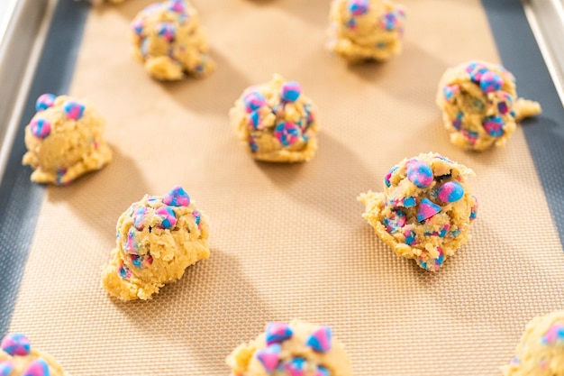 Chilled cookie dough scoops on the baking sheet to bake unicorn chocolate chip cookies.