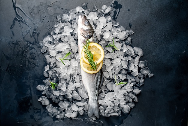 chilled raw sea bass and dorado fish with lemon and rosemary on ice, on a stone background