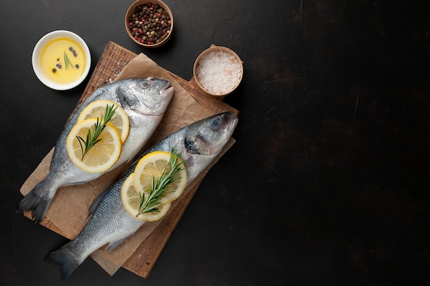 chilled raw sea bass and dorado fish with lemon and rosemary on a stone background  with copy space for your text