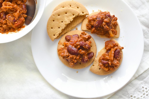 Chilli con carne with biscuits on a white plate