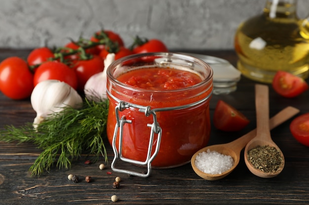 Chilli sauce, garlic, cherry tomatoes, olive oil, spices on wooden background, space for text. Closeup