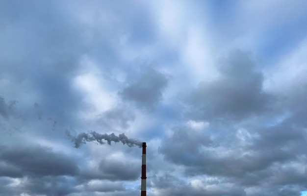 A chimney on the background of a cloudy sky Emissions of industrial waste into the atmosphere