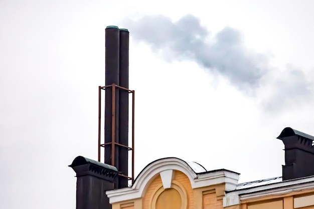 Chimney with smoke coming out of the heating stove on the roof of the building