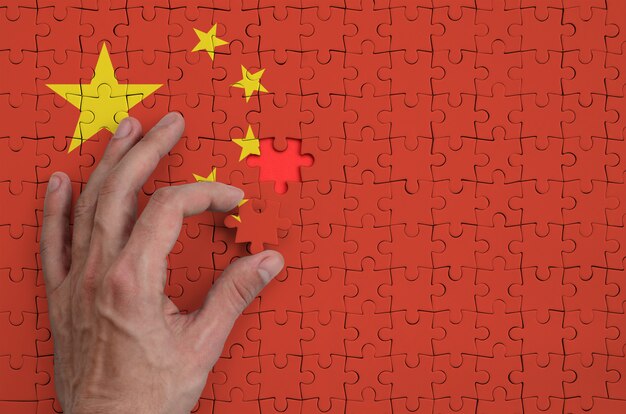 China flag  is depicted on a puzzle, which the man's hand completes to fold