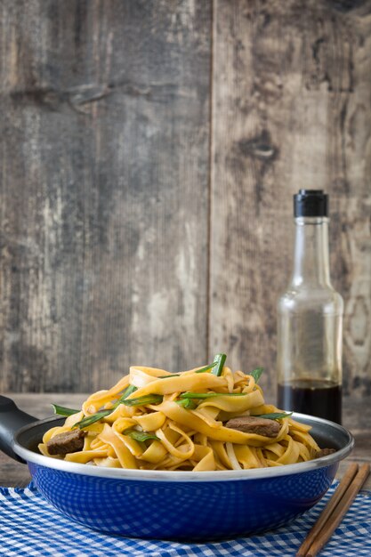 Chinees eten rundvlees chow mein in koekenpan op houten tafel op houten tafel