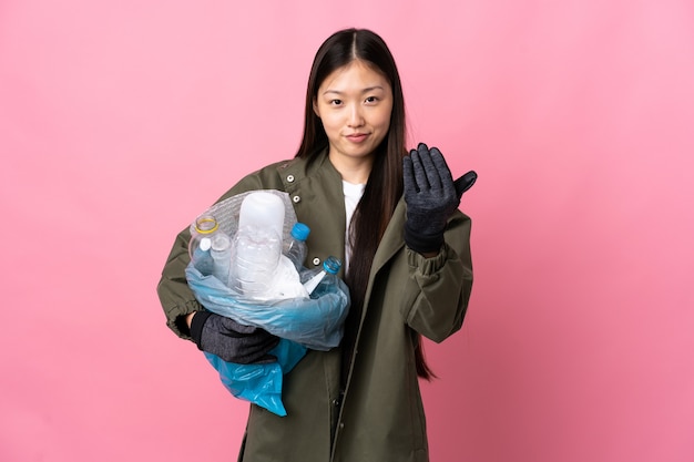 Chinees meisje dat een zak vol plastic flessen houdt om geïsoleerd te recyclen