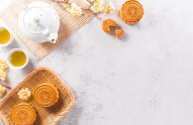 Chinees MidAutumn Festival concept gemaakt van mooncakes thee en pruimenbloesem op witte stenen achtergrond