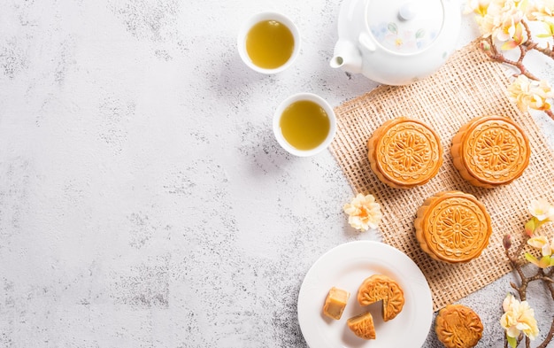 Chinees MidAutumn Festival concept gemaakt van mooncakes thee en pruimenbloesem op witte stenen achtergrond