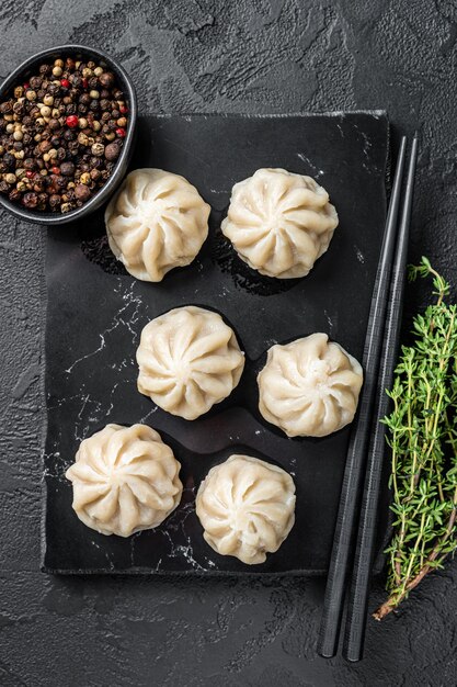 Chinese baozi dumplings on a marble board. Black background. Top view.