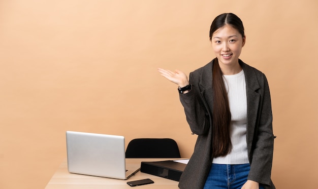 Chinese bedrijfsvrouw die in haar werkplaats copyspace denkbeeldig op de palm houden om een advertentie op te nemen