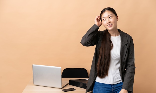 Chinese bedrijfsvrouw die op haar werkplaats een idee denkt