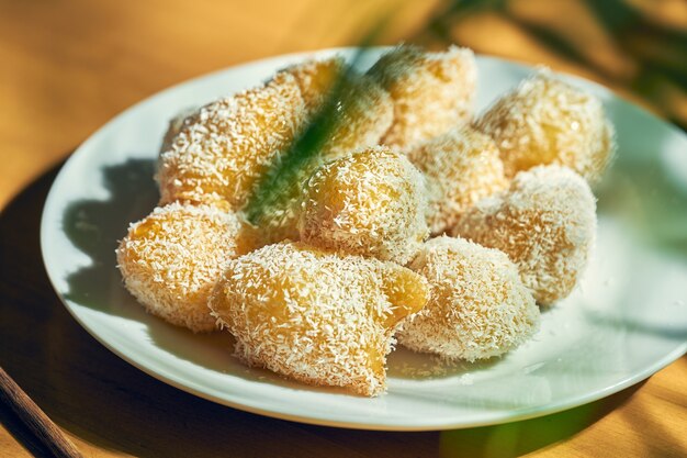 Chinese dessert - fried apples in caramel with coconut flakes in a white plate. Chinese cuisine