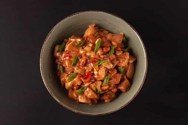 Chinese dish with chicken, chili, peanuts, sauces, and onions