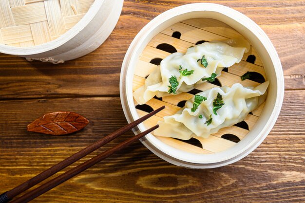 Chinese dumplings in wooden steamer with chopsticks