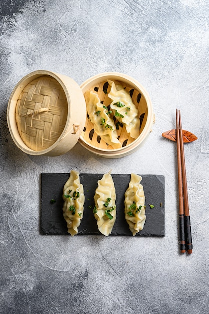 Chinese dumplings in wooden steamer with chopsticks