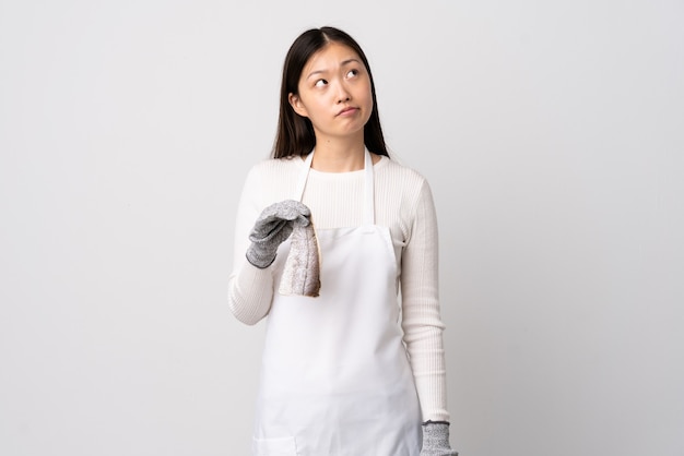 Chinese fishmonger wearing an apron and holding a raw fish isolated