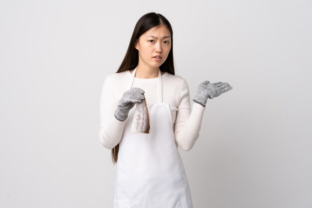 Chinese fishmonger wearing an apron and holding a raw fish isolated