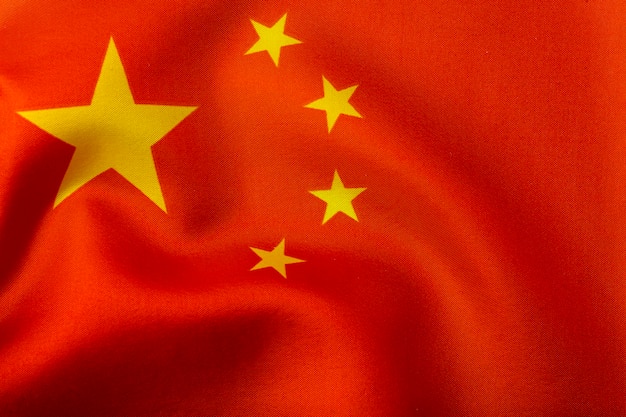 중국 국기. 빨간색 배경에 노란색 별과 중화 인민 공화국의 국기. 바람에 실크 주름과 섬유 및 직물 질감 중국 국기 | 프리미엄 사진