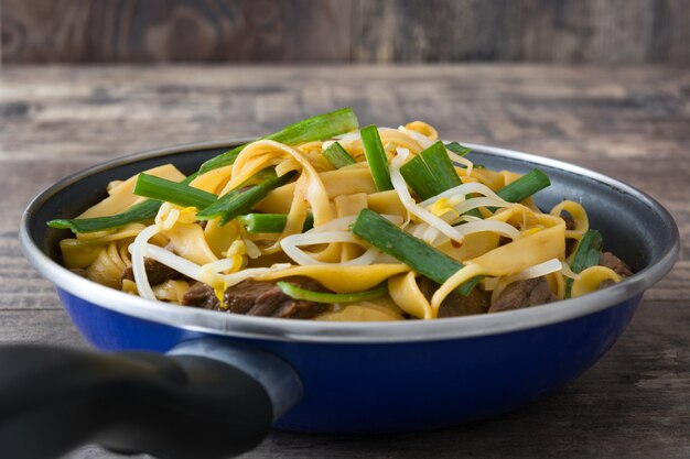 Chinese food beef chow mein on wooden table