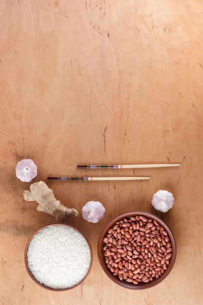 中華食材ナッツ野菜生姜根木の背景に生の米とスパイス調理用のニンニクとタマネギコピー スペース