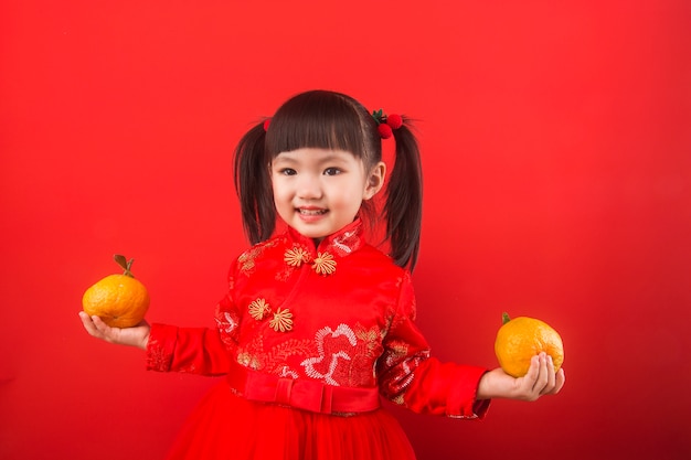 春祭りのためにオレンジを保持している中国の女の子