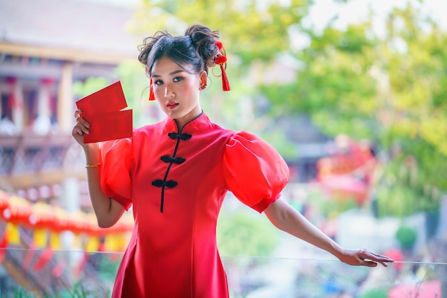 A chinese girl in a red dress is holding an qipao envelope