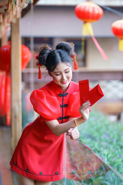 A chinese girl in a red dress is holding an qipao envelope