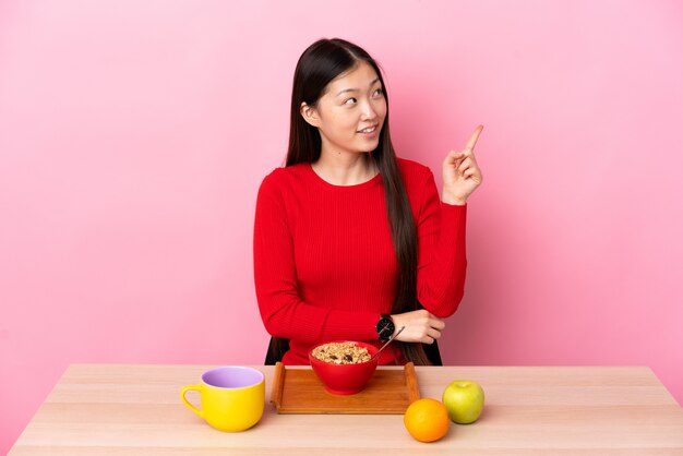 중국 여자는 테이블에 앉아 아침을 먹고