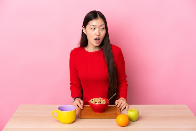 Китайская девушка сидит за столом и завтракает