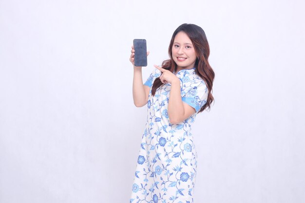 Chinese girl wearing Chinese blue dress happy and pointing at gadget on cell phone screen