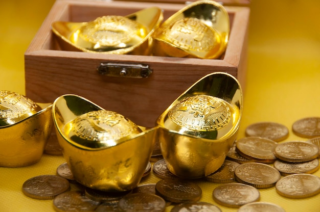 Chinese gold ingots and coins in treasure chest on yellow\
background