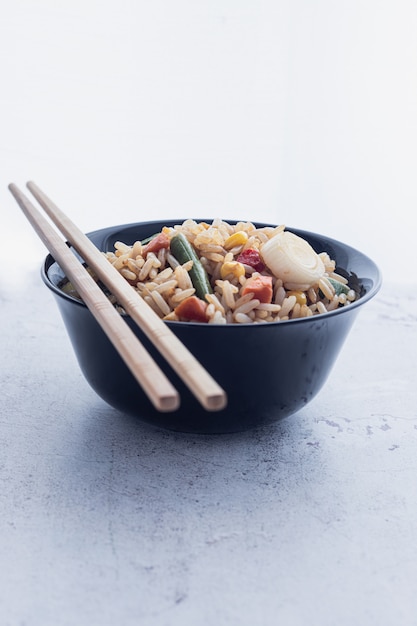 Chinese groente gebakken rijst en eieren geserveerd in een kom met stokjes. Chinese keuken