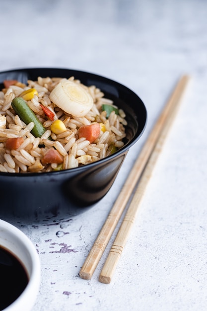 Chinese groente gebakken rijst en eieren geserveerd in een kom met stokjes en saus soja. Chinese keuken