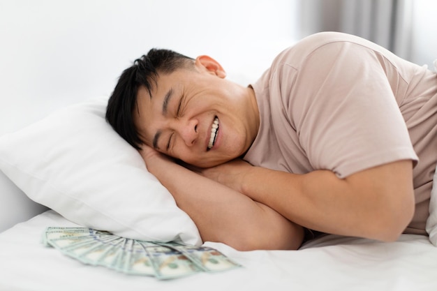 お金を枕の下に置いて睡眠を楽しむ中国人男性