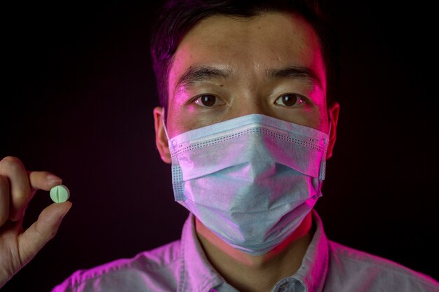 Chinese man in medical mask against 2019-nCov, pill in hand.