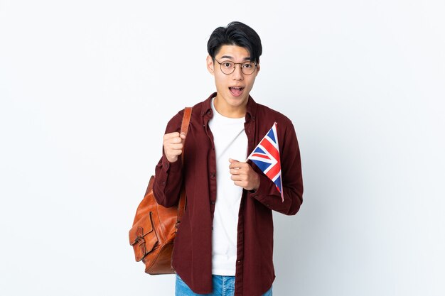 Chinese man met een britse vlag geïsoleerd op paarse achtergrond vieren een overwinning in winnaarspositie