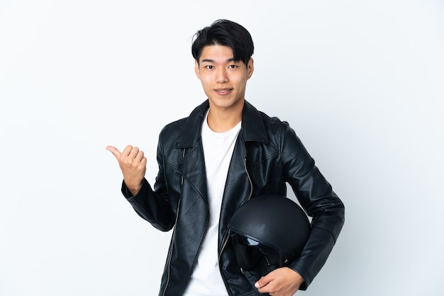 Chinese man with a motorcycle helmet isolated on white background pointing to the side to present a product